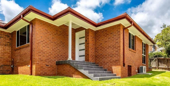 Modern brick home with landscaped yard showcasing custom design granny flats.