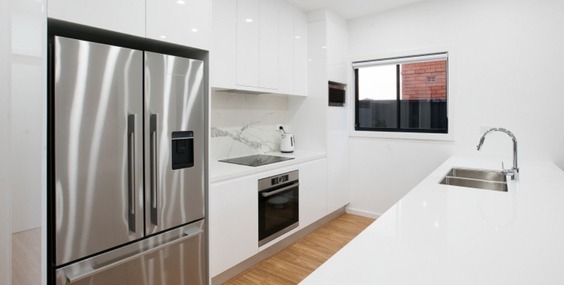 A modern white kitchen with stainless steel appliances and minimalist design, representing granny flat complying development standards.