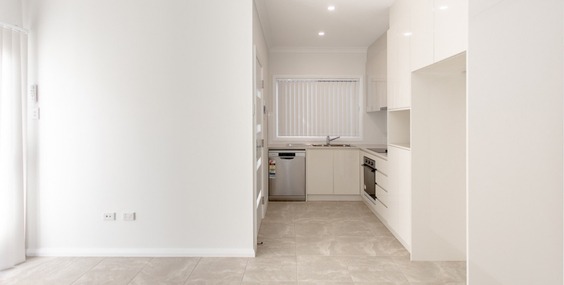 A clean modern kitchen with white cabinetry and appliances, representing practical and stylish granny flat kitchen designs.