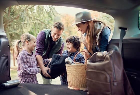 A smiling family unloads suitcases and household items from their car, ready to move into a new secondary dwelling funded by a flexible Granny Flat Loan.