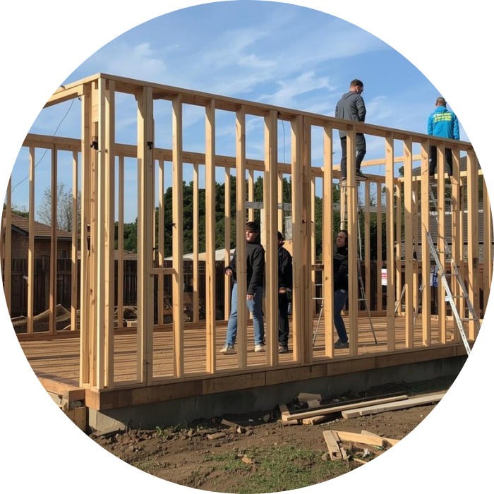 A group of workers building a wooden frame structure, representing granny flats construction in progress.